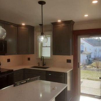 Charles Weiss Contracting - a kitchen with dark cabinets and white countertops - General Contractors Near Me