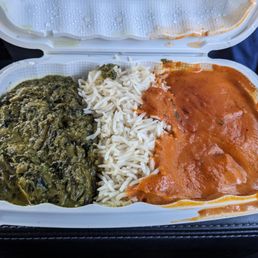 Saag Paneer - A takeout food container holds spinach curry, white rice, and paneer tikka masala, typical of Indian cuisine, served in a disposable container.