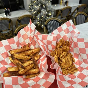 Chick'n Chill - Two baskets of French fries, one with seasoned fries and the other with waffle-cut fries, are held in front of a Christmas tree inside a restaurant. - Desserts Near Me - Rutherford, New Jersey