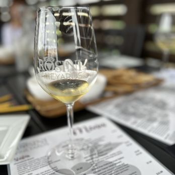 Rosini Vineyards - a glass of wine on a table - Wine Tasting Room Near Me - Rockwall, Texas