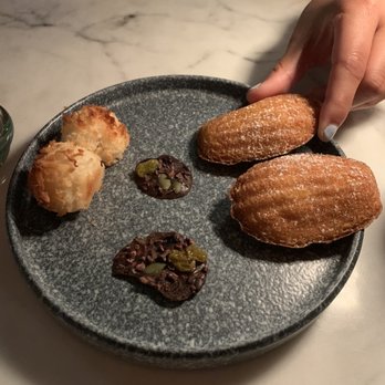 Bacchanalia - dessert plate that came with the check, coconut macaroon, madeline, and chocolate bite with some citrus! - New American Near Me - Atlanta, Georgia