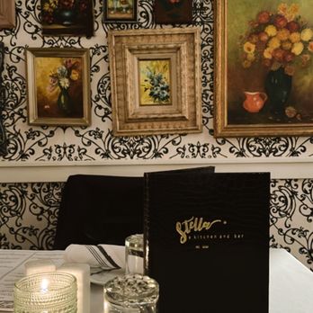 Stella - A Kitchen & Bar - a table with a menu and a candle - New American Near Me - Lakewood, New York Stella - A Kitchen & Bar - a table with a menu and a candle - New American Near Me - Lakewood, New York