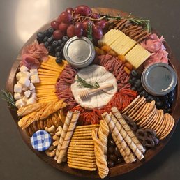 a platter of cheese, crackers, grapes, and meats
