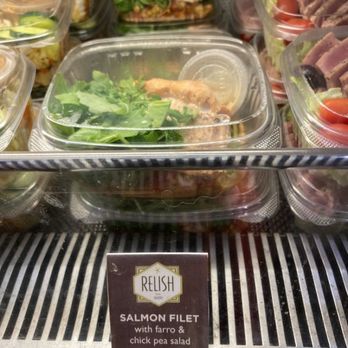 Relish - Salads to go...Salmon salad. - A clear plastic container holds a salmon filet with a side of farro and chickpea salad, displayed in a refrigerated case at Relish bakery and sandwich shop. - Bakeries Near Me - Provincetown, Massachusetts