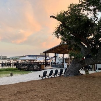 The Dock PCB - large outdoor uncovered area beside the bar under the oak trees with chairs and lawn. Amazing views of the lagoon and sunset - Beer Bar Near Me - Panama City Beach, Florida The Dock PCB - large outdoor uncovered area beside the bar under the oak trees with chairs and lawn. Amazing views of the lagoon and sunset - Beer Bar Near Me - Panama City Beach, Florida
