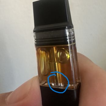 Pasadena Wellness - tampered - A handheld vape device with a transparent tank showing liquid, held by a person's fingers, with a blue circle highlighting a component. - Cannabis Dispensaries Near Me - Pasadena, California