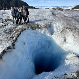 Family standing over a waterfall inside the glacier Family standing over a waterfall inside the glacier
