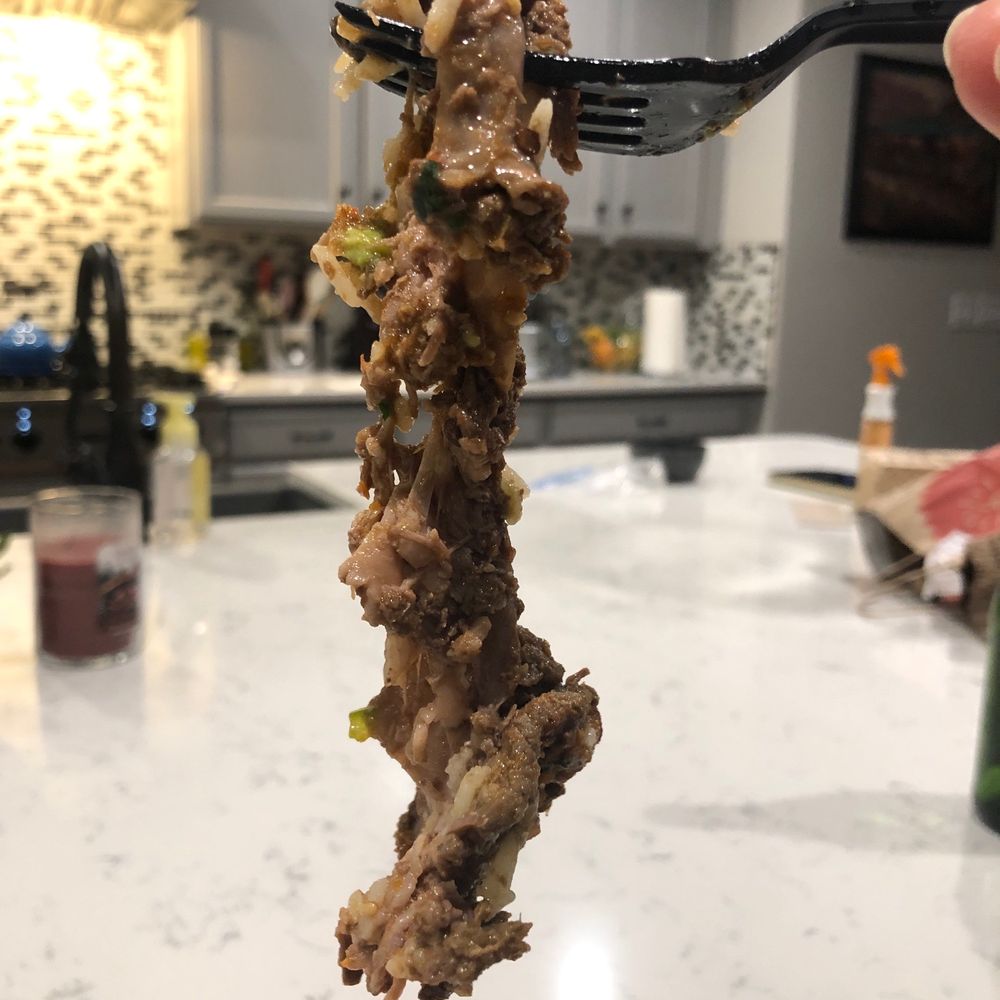 a hand holding a fork full of food