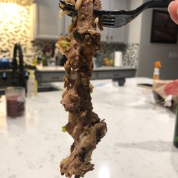 a hand holding a fork full of food