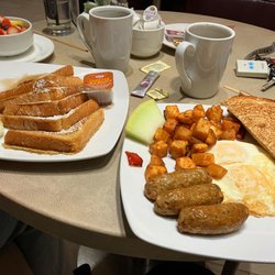 Brix Kitchen & Cocktails - On the left, fresh fruit and French toast. Plate on the right is two eggs, fried seasoned potatoes, sourdough toast and 3 chicken sausages.