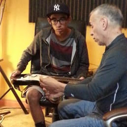 Xavier teaching my son how to string up an electric guitar.