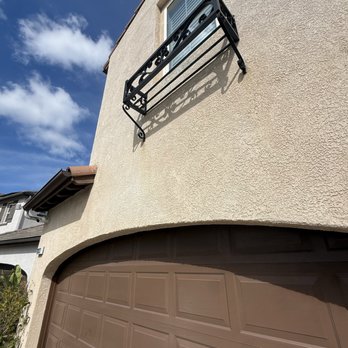 Iron Duck Exteriors - Before: heavy iron runoff beneath wrought iron, vertical streaking down stucco, buildup locking into the surface. - Pressure Washers Near Me - Palmdale, California Iron Duck Exteriors - Before: heavy iron runoff beneath wrought iron, vertical streaking down stucco, buildup locking into the surface. - Pressure Washers Near Me - Palmdale, California