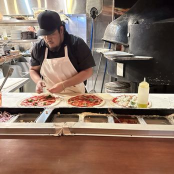 All'Acqua - Our pizzaio working hard at making pizzas while also manning the wood fired oven behind him - Italian Near Me - Los Angeles, California