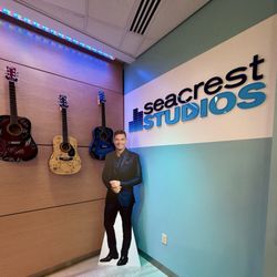 Cardboard cutout of Ryan Seacrest next to signed guitars