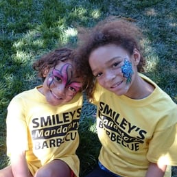 Two cute kids show off their painted faces at a bbq.