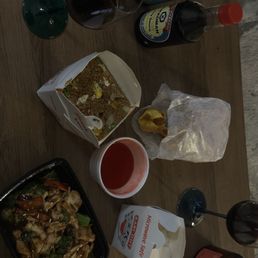 The table holds Chinese dishes like fried rice and stir-fry, along with drinks including wine and soda, and condiments such as soy sauce.