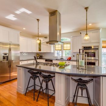 G.B. Construction and Development - Kitchen with white cabinets, stainless steel appliances, a gray island and glass backsplash. - General Contractors Near Me - Ronkonkoma, New York