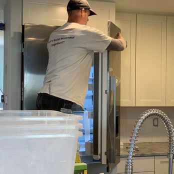 Total Construction - a man working on a refrigerator - General Contractors Near Me - Seattle, Washington