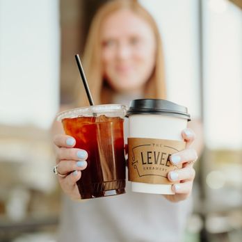 Levee Coffee & Creamery - a woman holding two cups of coffee - Ice Cream & Frozen Yogurt Near Me - Collierville, Tennessee Levee Coffee & Creamery - a woman holding two cups of coffee - Ice Cream & Frozen Yogurt Near Me - Collierville, Tennessee