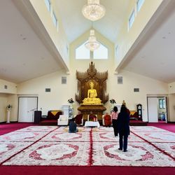 Burma Buddhist Temple - Buddhist prayer hall,  golden Buddha statue, guests and monks in meditation and reflection.