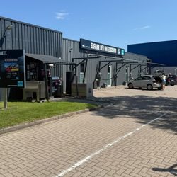 BEST CARWASH Hamburg Nord - Gesamtansicht der Anlage mit mehreren Staubsaugerplätzen, Parkplatz und viel Platz für die Fahrzeugpflege vor und nach der Wäsche.
