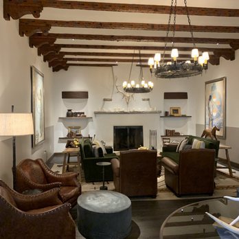 SkyFire - Wonderfully decorated interior - A living room features a fireplace, wooden ceiling beams, and seating including leather and upholstered chairs, with artwork on the walls. - American Near Me - Santa Fe, New Mexico