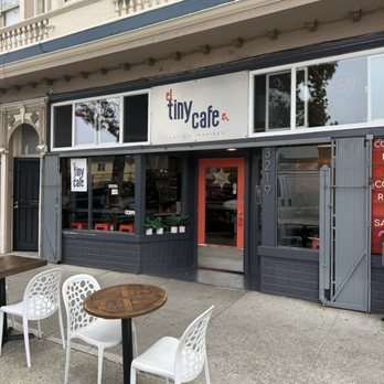 El Tiny Cafe - The image shows the storefront of El Tiny Cafe with outdoor tables and chairs, signage, and a partially open door. - Cafes Near Me - Berkeley, California