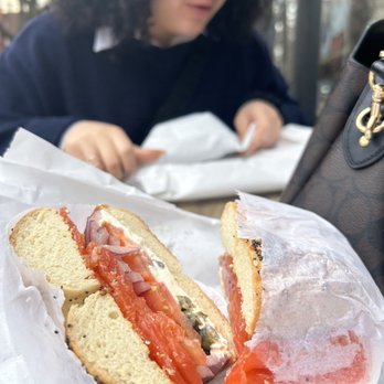 Bagel World - a woman eating a bagel sandwich - Bagels Near Me - Brooklyn, New York