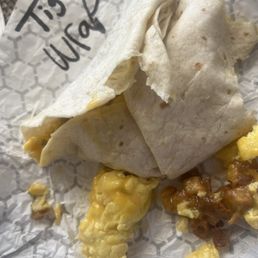"Tightly Wrapped Burrito?" - A breakfast burrito wrapped in a flour tortilla, with visible scrambled eggs and cheese, accompanied by scrambled eggs and salsa on a paper-lined tray.
