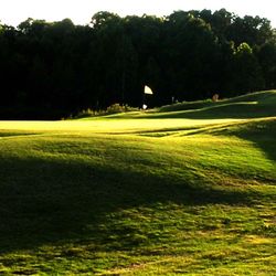 Kirkwood National Golf Club - Sun setting over the green on 18, which is a par 4 and measures 437 yards from the tips. Water comes into play at the tee boxes and greens.
