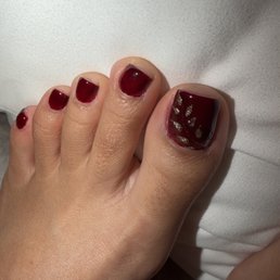 Gel pedicure with burgundy polish color and gold design