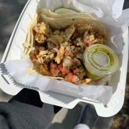 A taco, with tomatoes, cilantro, chicken, a side of lime and the green sauce i dont know what it is called A taco, with tomatoes, cilantro, chicken, a side of lime and the green sauce i dont know what it is called