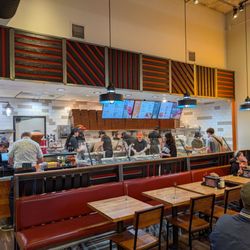 Order counter with menu. Staff building and preparing the pizza.