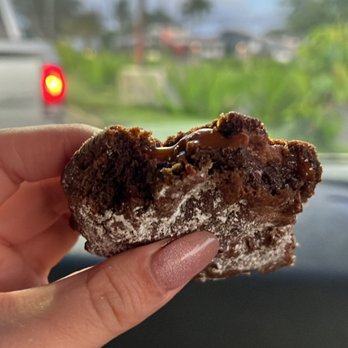 Chunky - a hand holding a half eaten doughnut - Food Trucks Near Me - Laie, Hawaii