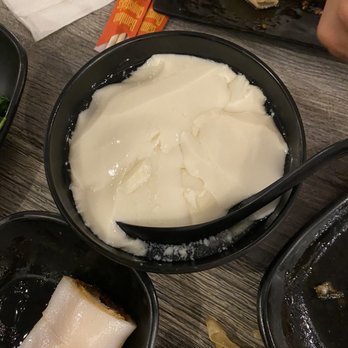 IT DIMSUM - A black bowl filled with a white, smooth, and creamy dessert, likely a traditional Asian sweet dish, on a wooden table at a dim sum restaurant. - Dim Sum Near Me - Albuquerque, New Mexico