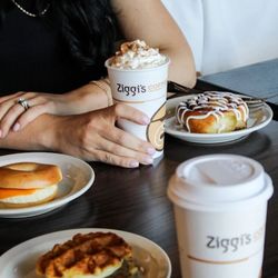 Ziggi's Coffee - Breakfast table with Ziggi's hot coffee cups, cinnamon roll, and breakfast sandwiches.