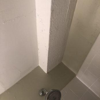 Olde Harbour Inn - Bathroom shower head covered in limescale buildup and peeling paint water stained walls - Hotels Near Me - Savannah, Georgia