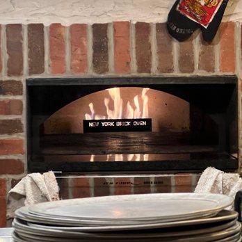 BarDough - a stack of plates in front of a brick oven - Bars Near Me - New York, New York