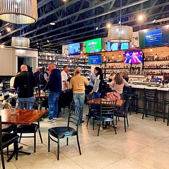 Keg N Bottle - Interior view from the left side. 3 TVs behind the bar, 4 TVs in front of the bar, and one larger screen TV on the back wall. - Beer, Wine & Spirits Near Me - San Diego, California