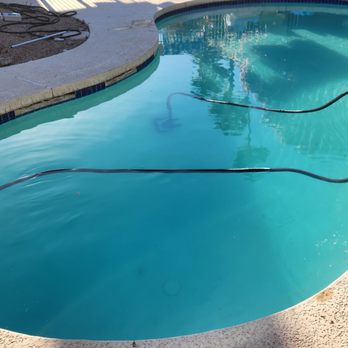 T's Pools - After - A swimming pool with clear water, surrounded by a concrete deck, with hoses and cleaning tools visible on the side. - Pool Cleaners Near Me - Phoenix, Arizona
