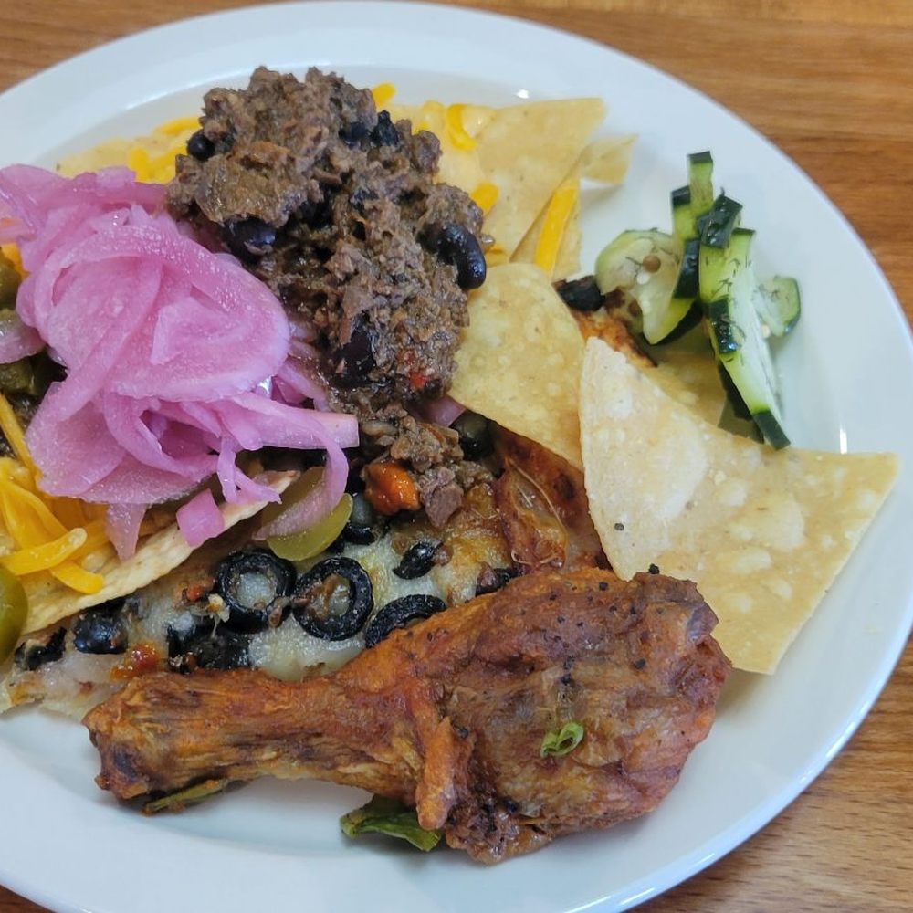 Dosan A Social Eatery - Build your own nachos, pizza slice buried beneath, buffalo sauce style chicken, pickled onions on top of nachos and some [homemade?] pickles - New American Near Me - Clovis, California