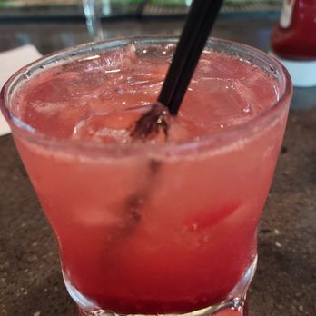 Uptown Kitchen - Amelia Earhart - A pink-colored cocktail with ice cubes and two black straws in a short glass, placed on a bar or restaurant counter. - New American Near Me - Granger, Indiana