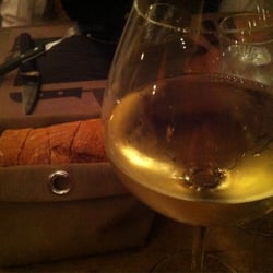Les Planches - Verre de Chardonnay et panier à pain sous les lumières de la terrasse.