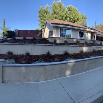 Mulch And Landscaping Design - a house with a retaining wall - Landscaping Near Me