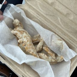 Garlic parmesan - Chicken wings coated in garlic parmesan sauce are placed in a paper-lined takeout box, ready for eating.