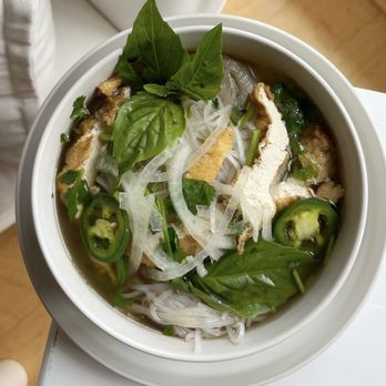 Pho 14 - pho - A bowl of Vietnamese pho featuring fresh herbs, sliced jalapeños, onions, and rice noodles, served in a white bowl. - Vietnamese Near Me - Washington, DC, District of Columbia