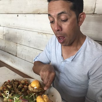 Mongers Market + Kitchen - Breaking a poached egg on his Low Country Benedict. - Seafood Near Me - Austin, Texas Mongers Market + Kitchen - Breaking a poached egg on his Low Country Benedict. - Seafood Near Me - Austin, Texas