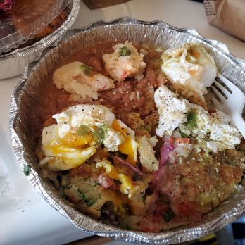 Fonda Garibaldi - Crabcake Benedict with Chipotle sauce and beans.  Brunch.   So good. - A foil container contains a breakfast dish with poached eggs, potatoes, beans, and seasonings, served with a plastic fork. - New Mexican Cuisine Near Me - Brooklyn, New York