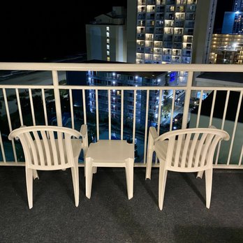 Coral Beach Resort - 2 plastic chairs and table on balcony . - Hotels Near Me - Myrtle Beach, South Carolina