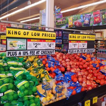 Food King - How prices work - Display of citrus fruits and tomatoes at Food King grocery store in Albuquerque, with signage indicating low prices and a 10% checkout fee. - Grocery Near Me - Albuquerque, New Mexico